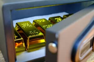 Steel safes box full of coins stack and gold bar on the wooden table